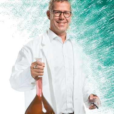 Prof. Barcikowski mit Nanogold aus Laserabtrag in riesigem Reagenzglas.