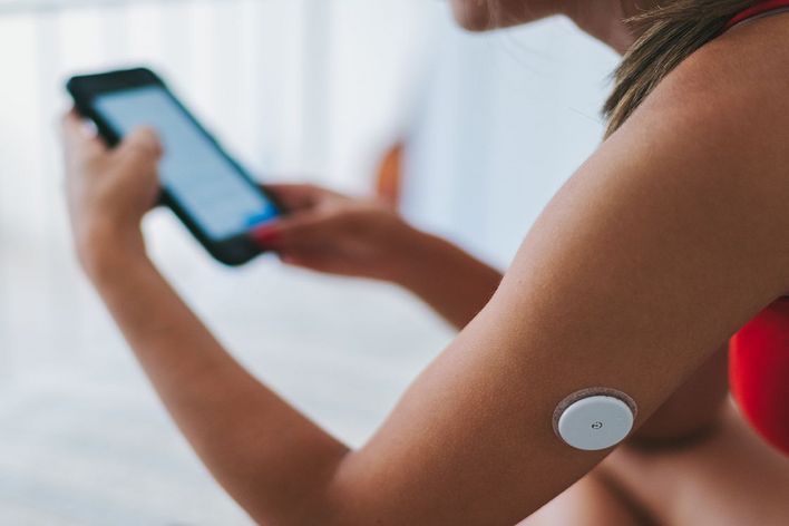 Woman with diabetes monitoring blood sugar on phone
