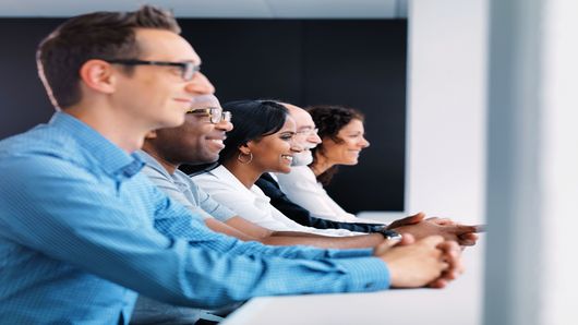 TRUMPF employees sitting in a row and laughing