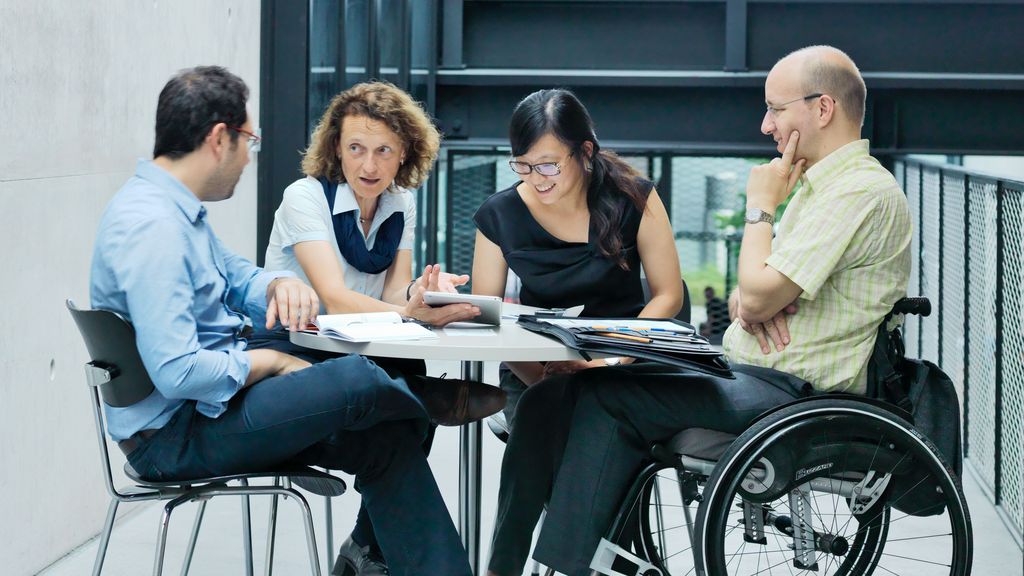 TRUMPF employees talking to each other while sitting on a table