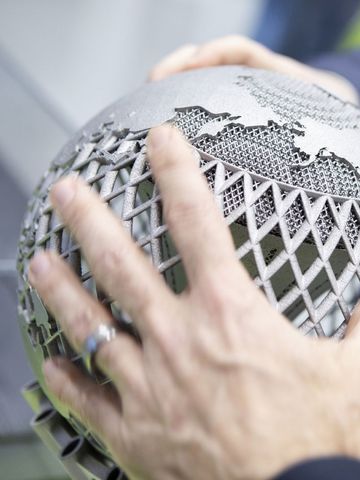 People encircle a metal globe
