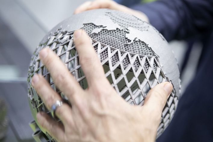People encircle a metal globe