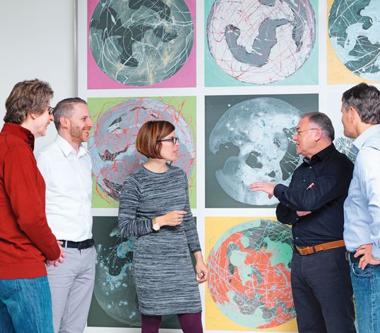 TRUMPF employees talking in front of part of a painting