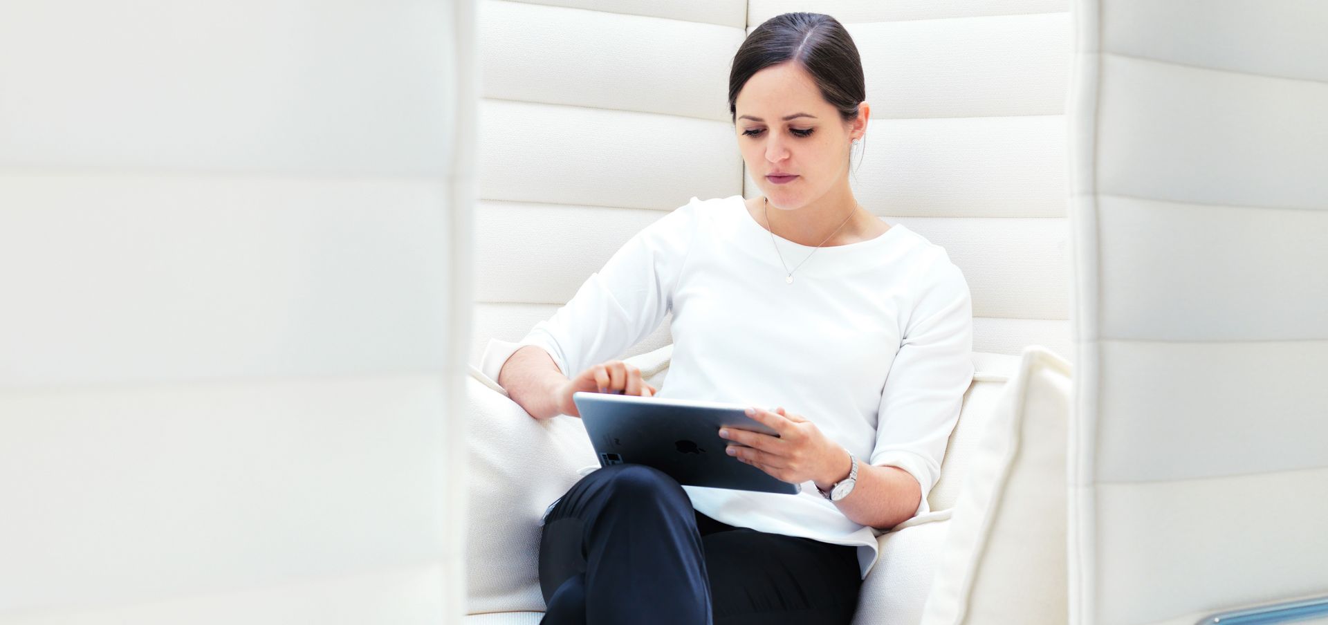 A TRUMPF employee sitting in the lounge area and working with a mobile device